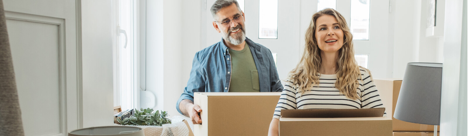 Middle aged couple moving in boxes to new home