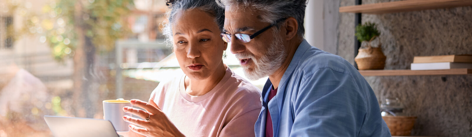 Mature couple using laptop and drinking coffee at home